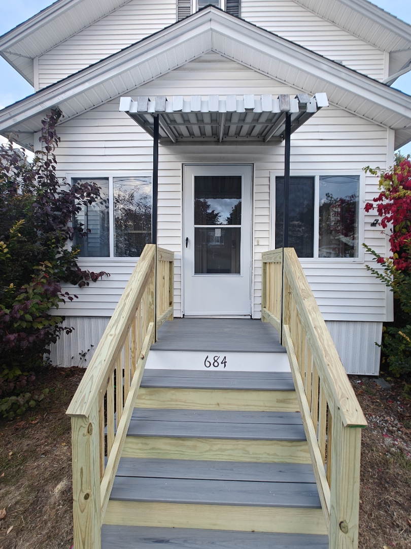 Front steps after rebuild with fresh railings and clean finish