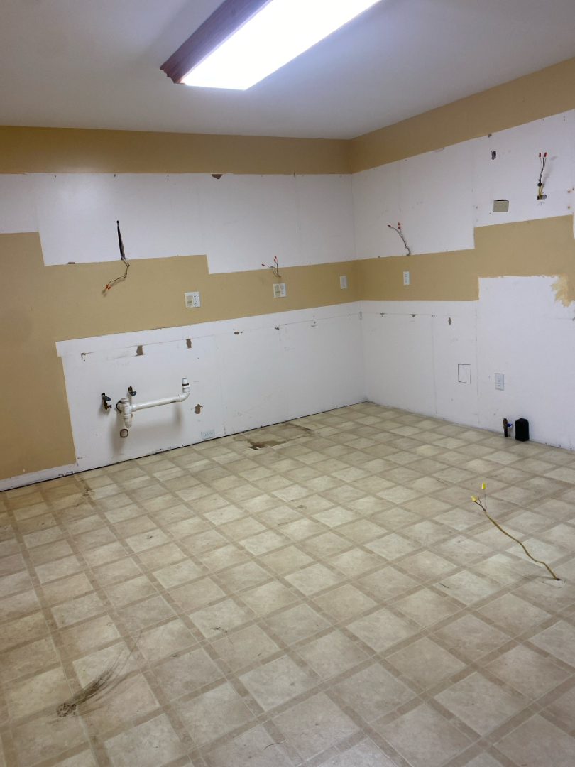 Kitchen before remodel with older flooring and cabinets removed