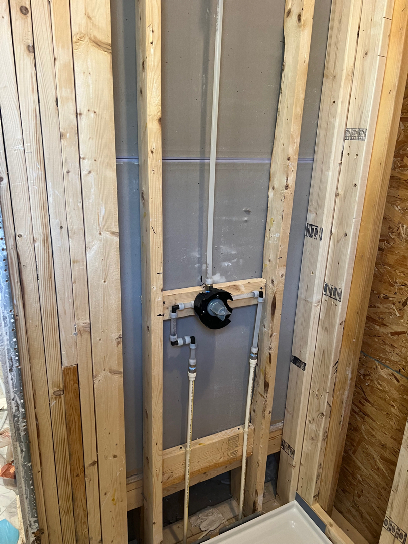 Shower before renovation with open framing and older materials